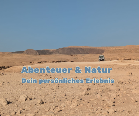 Wüstenlandschaft mit einem Fahrzeug auf einer entfernten Straße unter blauem Himmel.